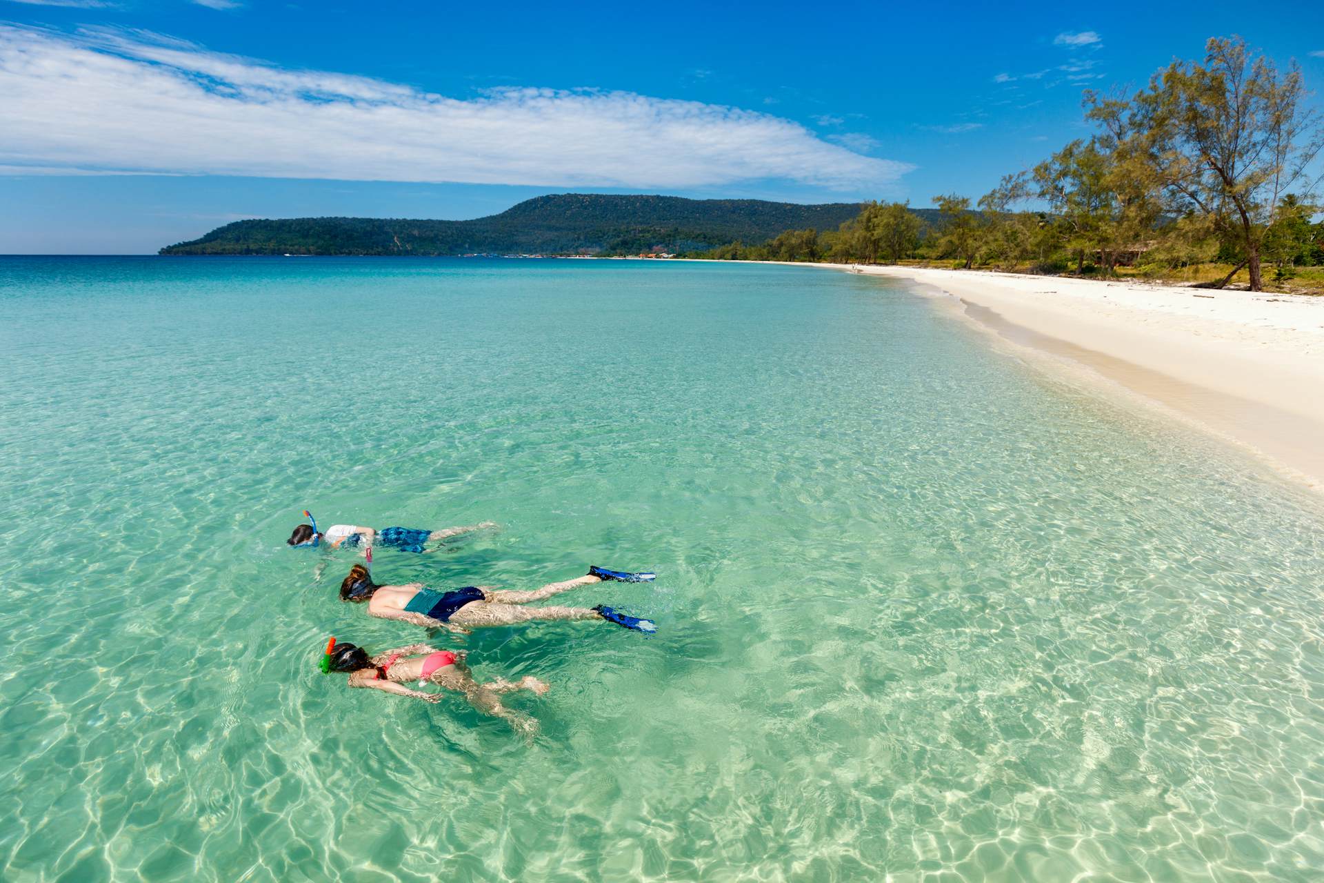 A mother and kids snorkeling in clear tropical water on an empty beach on Koh wrong, Cambodia